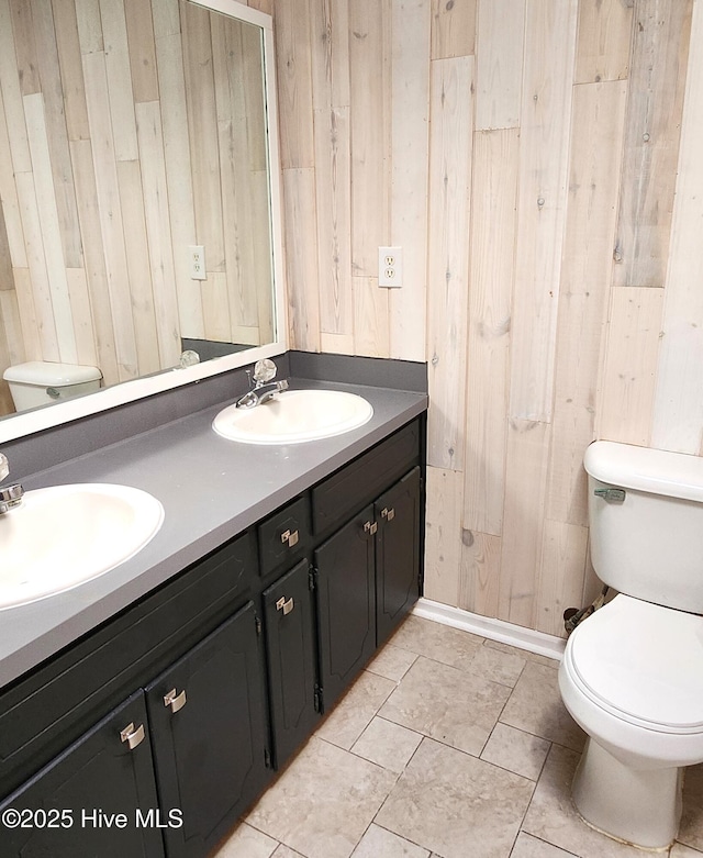 bathroom with vanity, toilet, and wood walls