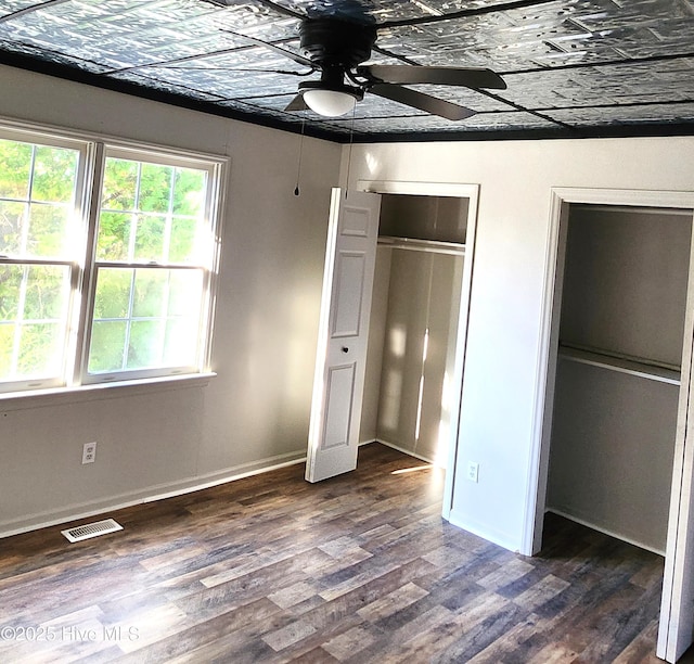 unfurnished bedroom featuring multiple windows, ceiling fan, and dark hardwood / wood-style floors