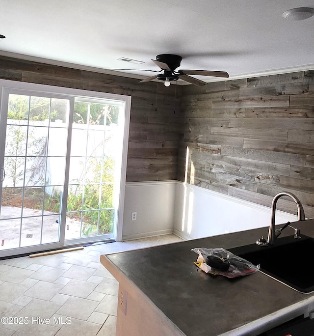 kitchen with ceiling fan and wood walls