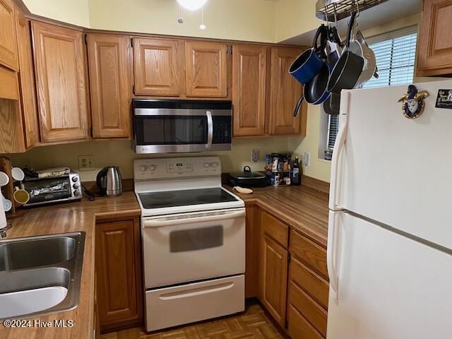 kitchen with sink, dark parquet floors, and white appliances