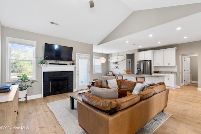 living room featuring light hardwood / wood-style floors, a fireplace, and vaulted ceiling