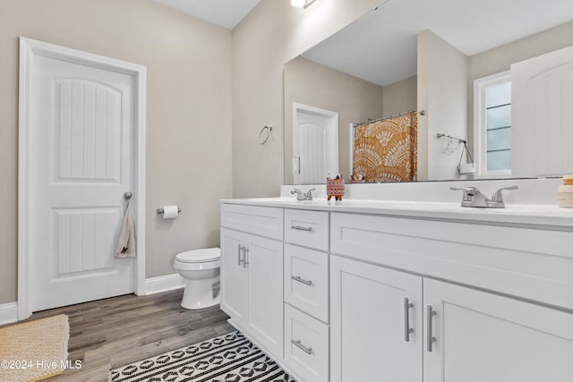 bathroom with hardwood / wood-style floors, vanity, toilet, and walk in shower