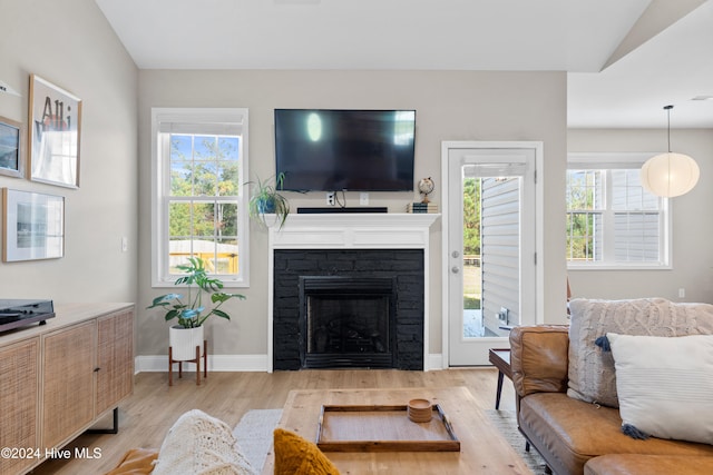 living room with a wealth of natural light, a fireplace, light hardwood / wood-style floors, and lofted ceiling