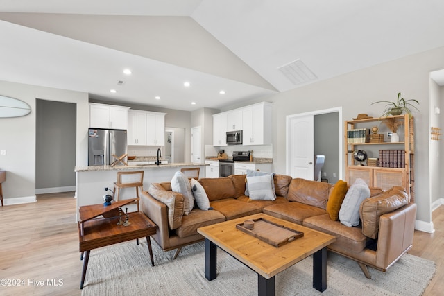 living room featuring light hardwood / wood-style floors, sink, and high vaulted ceiling