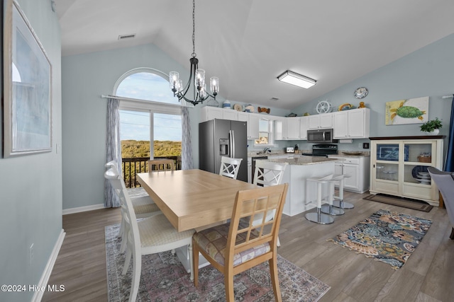 dining area with a notable chandelier, wood-type flooring, sink, and vaulted ceiling