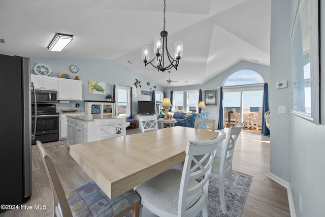 dining space with ceiling fan with notable chandelier, light wood-type flooring, and lofted ceiling