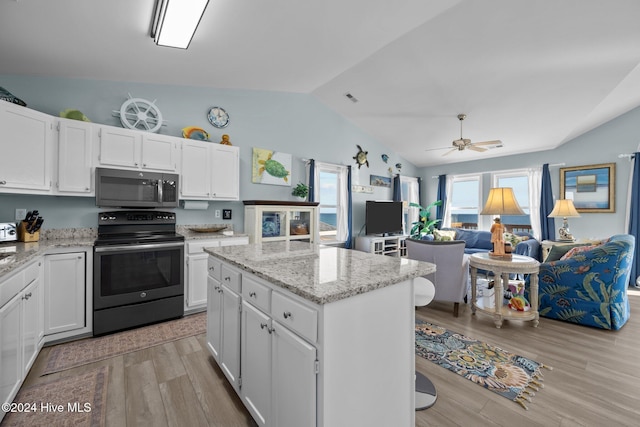 kitchen with appliances with stainless steel finishes, light hardwood / wood-style flooring, a center island, white cabinetry, and lofted ceiling