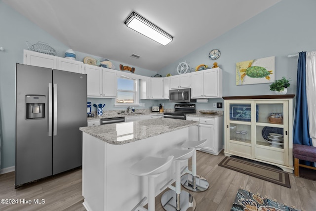 kitchen featuring appliances with stainless steel finishes, light hardwood / wood-style flooring, white cabinets, a kitchen island, and lofted ceiling