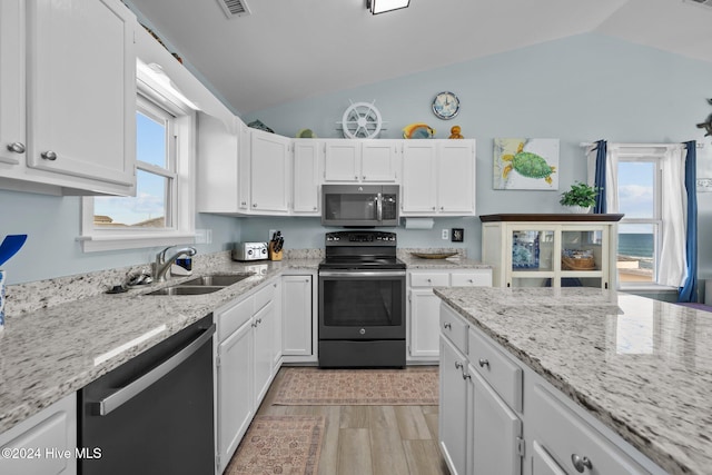 kitchen featuring white cabinets, a wealth of natural light, appliances with stainless steel finishes, and vaulted ceiling