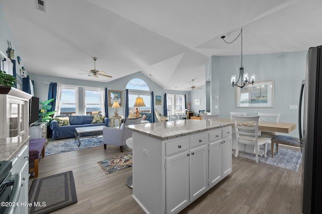 kitchen with stainless steel fridge, vaulted ceiling, light hardwood / wood-style flooring, a center island, and white cabinetry