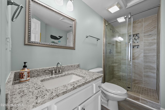 bathroom featuring hardwood / wood-style floors, vanity, toilet, and a shower with shower door