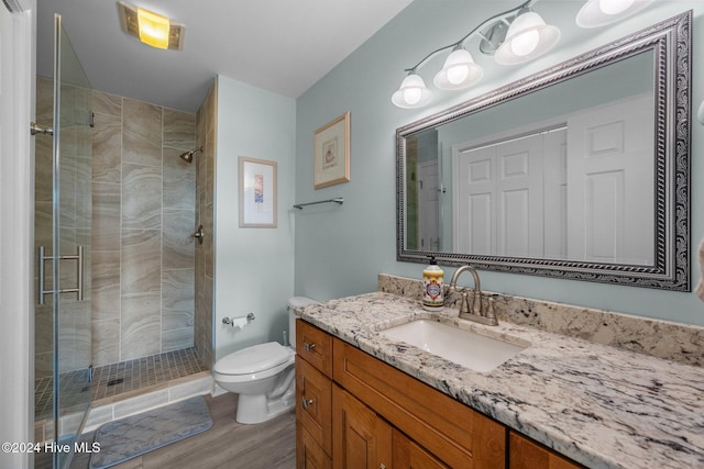 bathroom with hardwood / wood-style flooring, vanity, toilet, and a shower with shower door