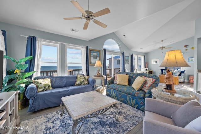 living room with ceiling fan, a water view, lofted ceiling, and light hardwood / wood-style flooring