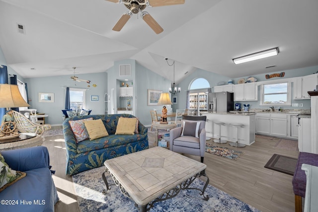 living room featuring plenty of natural light, light hardwood / wood-style floors, lofted ceiling, and sink