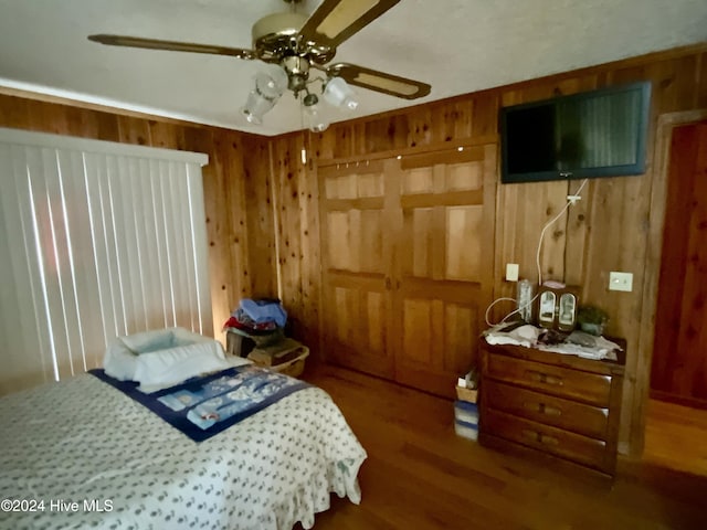 bedroom featuring wood walls, dark hardwood / wood-style flooring, and ceiling fan