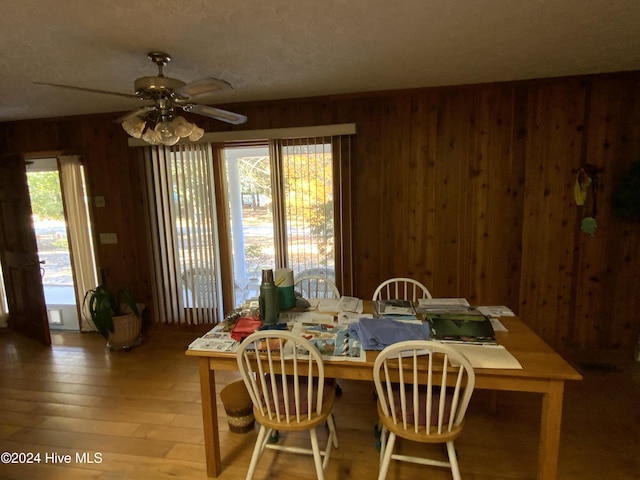 dining space with hardwood / wood-style flooring, plenty of natural light, and wooden walls