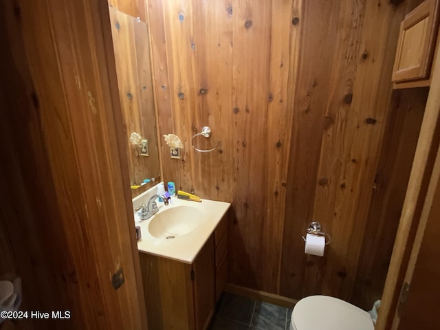 bathroom with tile patterned flooring, vanity, toilet, and wooden walls