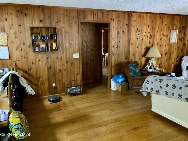 bedroom featuring hardwood / wood-style flooring, wood walls, ornamental molding, and a textured ceiling