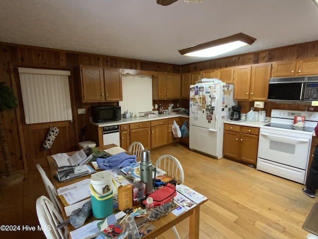 kitchen with wood walls, ceiling fan, light hardwood / wood-style floors, and white appliances