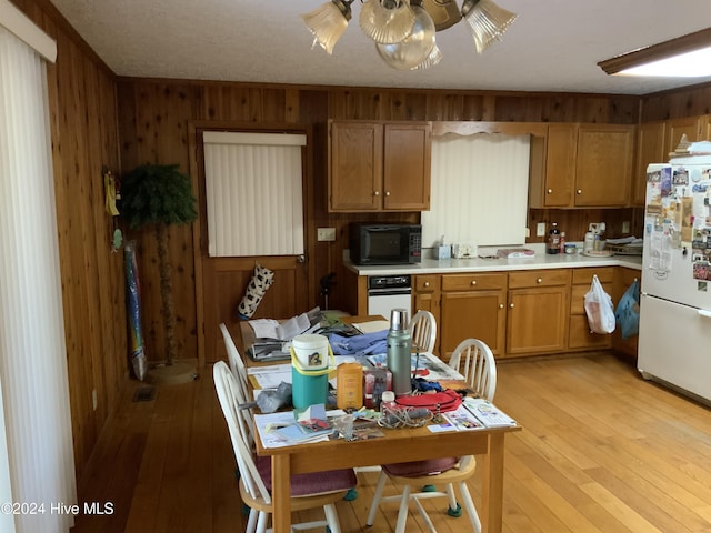 kitchen with wooden walls, light hardwood / wood-style floors, and white appliances