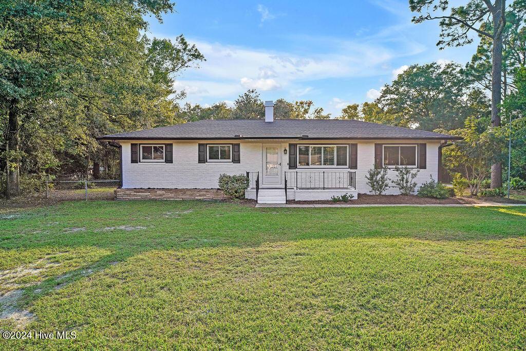 ranch-style house featuring covered porch and a front lawn