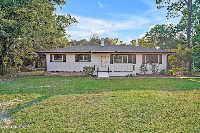 ranch-style house featuring covered porch and a front lawn