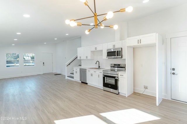 kitchen featuring pendant lighting, white cabinets, stainless steel appliances, and light hardwood / wood-style flooring