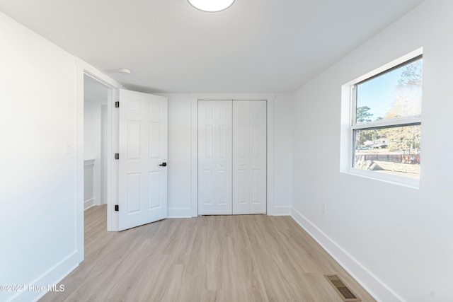 unfurnished bedroom with light hardwood / wood-style floors and a closet