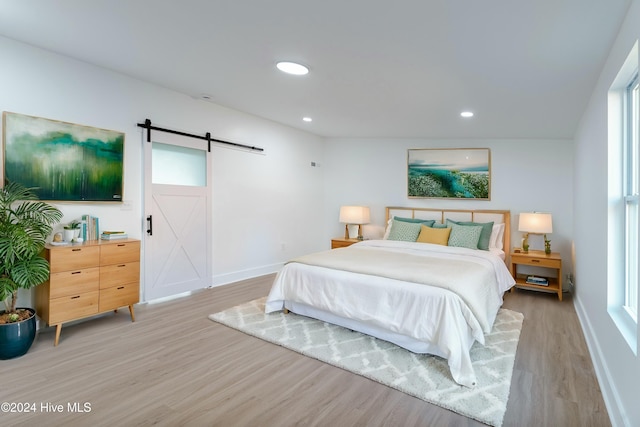 bedroom with a barn door and light hardwood / wood-style floors