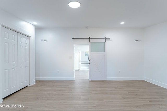 empty room with a barn door and light hardwood / wood-style floors