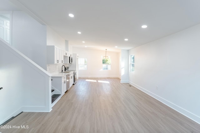 unfurnished living room featuring sink and light hardwood / wood-style flooring