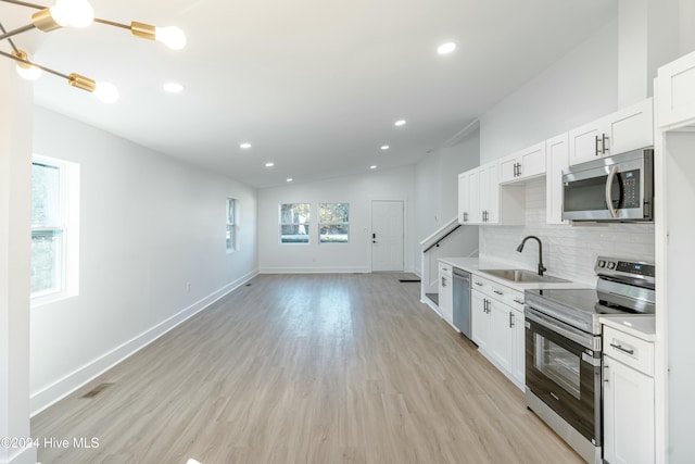 kitchen featuring sink, stainless steel appliances, lofted ceiling, decorative backsplash, and white cabinets