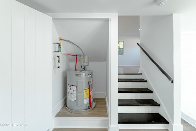 stairs featuring hardwood / wood-style flooring and water heater