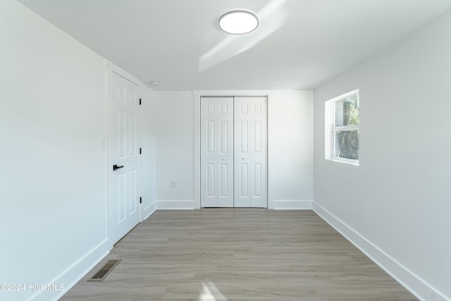 unfurnished bedroom with a closet and light hardwood / wood-style flooring