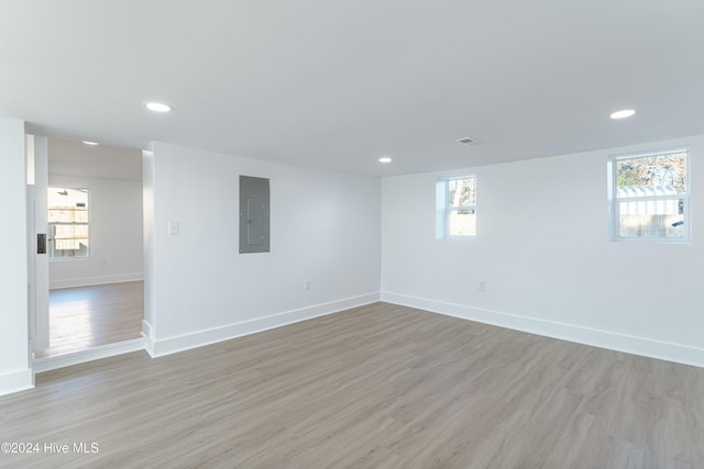 unfurnished room featuring electric panel, a healthy amount of sunlight, and light hardwood / wood-style floors