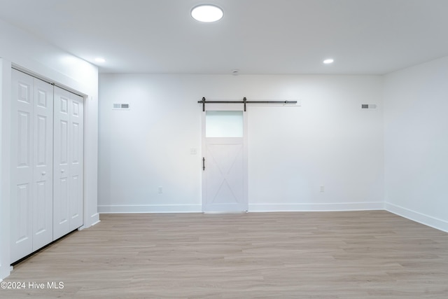 empty room featuring a barn door and light hardwood / wood-style flooring