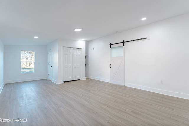 unfurnished room with a barn door and light hardwood / wood-style floors