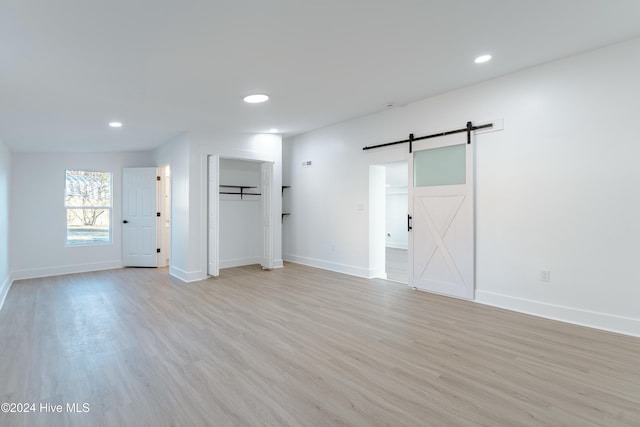 empty room with a barn door and light hardwood / wood-style flooring