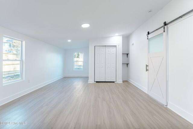 empty room featuring a barn door, plenty of natural light, and light wood-type flooring