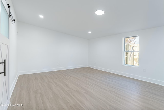 empty room with a barn door and light hardwood / wood-style floors