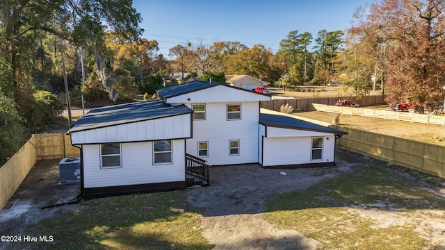 rear view of house with a lawn and central AC unit