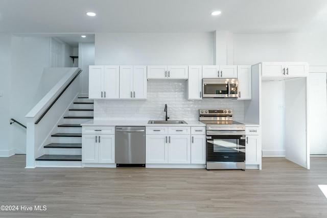 kitchen with white cabinetry, sink, decorative backsplash, appliances with stainless steel finishes, and light wood-type flooring