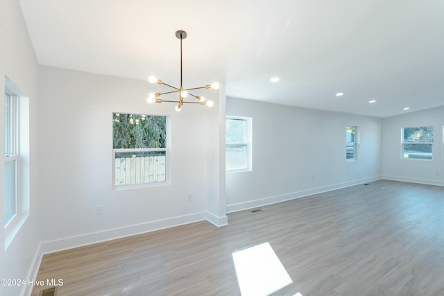 empty room with a chandelier and light hardwood / wood-style floors