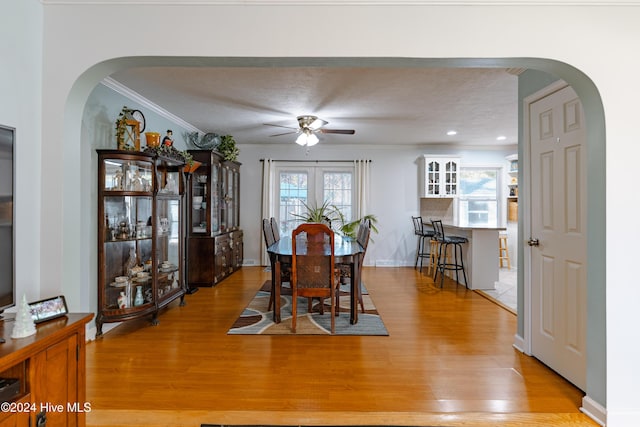 dining space with french doors, crown molding, light hardwood / wood-style flooring, ceiling fan, and a textured ceiling