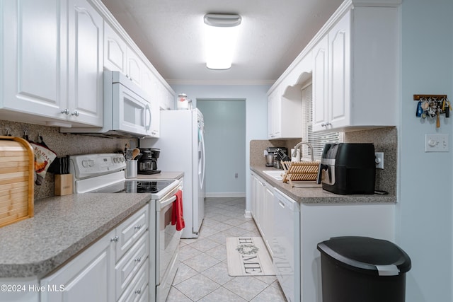 kitchen with white appliances, sink, ornamental molding, light tile patterned floors, and white cabinetry