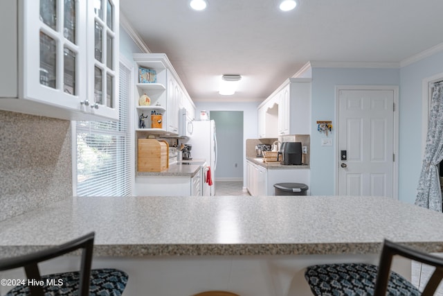 kitchen featuring white cabinets, decorative backsplash, kitchen peninsula, and ornamental molding