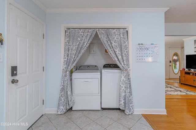 clothes washing area featuring ornamental molding, light hardwood / wood-style flooring, and washing machine and clothes dryer