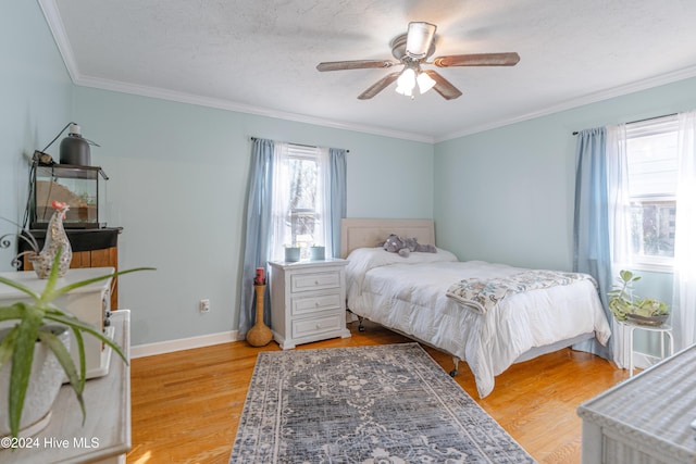 bedroom with ceiling fan, crown molding, light hardwood / wood-style floors, and a textured ceiling