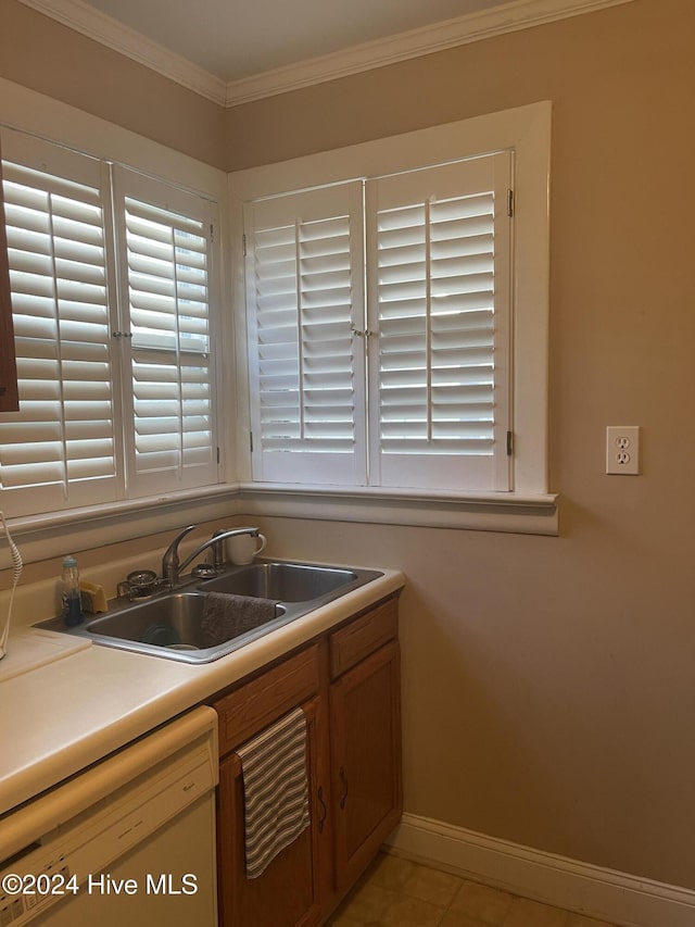 kitchen featuring white dishwasher, crown molding, light tile patterned floors, and sink