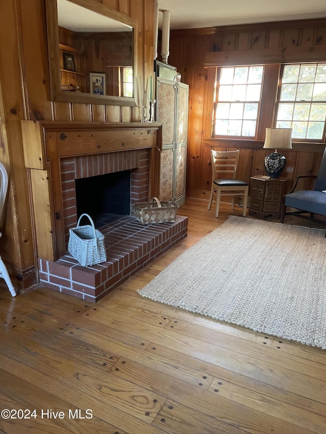 living room featuring hardwood / wood-style floors, wooden walls, and a brick fireplace